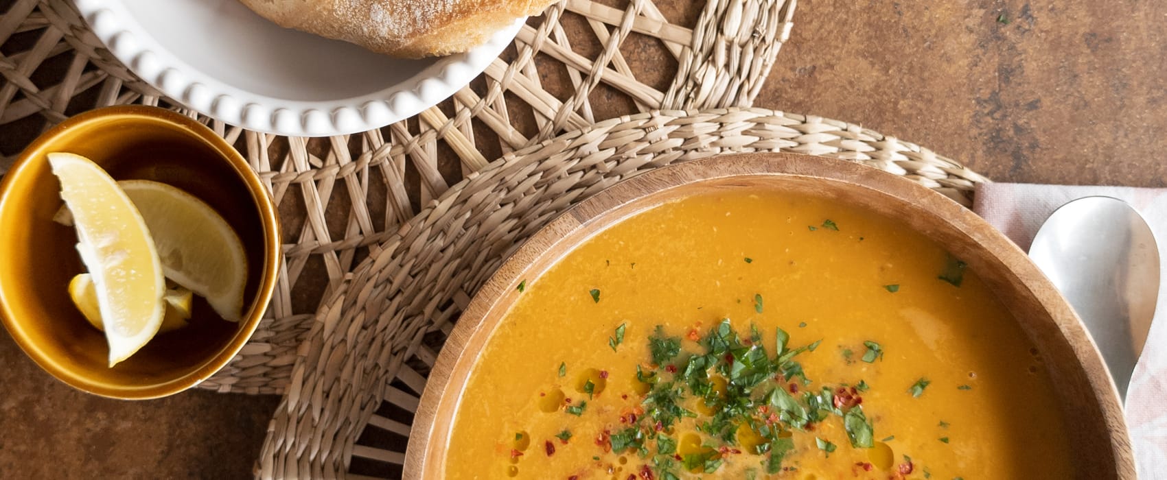 Schale mit Brot gereicht zu einem Teller Türkischer Linsensuppe, serviert mit Zitrone