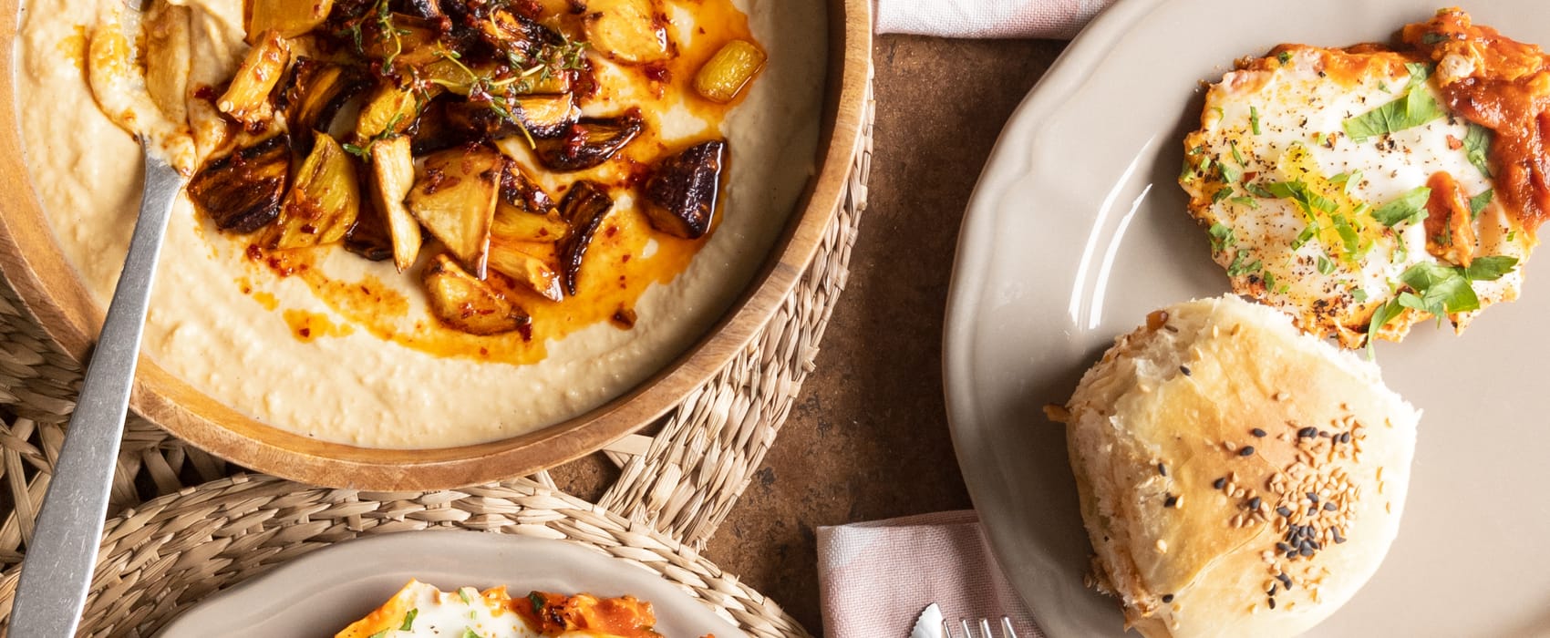 Selbstgebackene Dinkelbrötchen, Eier auf Tomatensoße und pikanter Hummus mit Wurzelgemüse