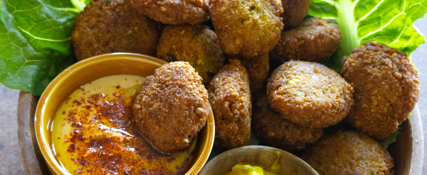 Schale mit selbstgemachten Falafel, Salat, Hummus und Mango-Dip
