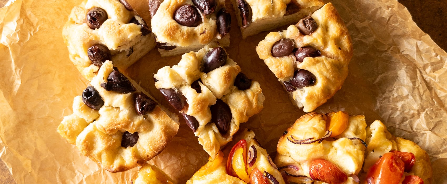 Zweierlei Focaccia: eine belegt mit Oliven, die andere mit Cherrytomaten und roten Zwiebeln. 