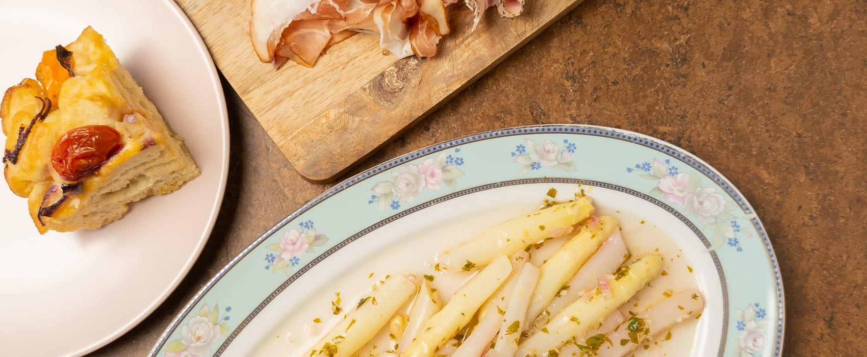 Marinierter weißer Spargel angerichtet auf einer frühlingshaften Platte.