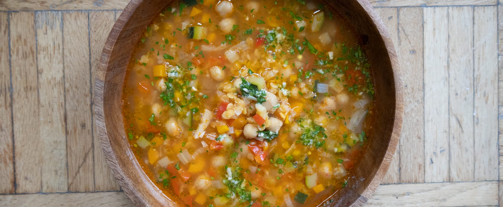 Holzschüssel mit italienischer Minestrone garniert mit Pesto